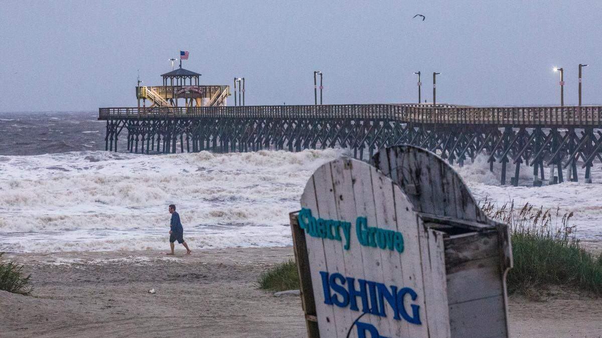 A man leans into the wind as he walks the beach near Cherry Grove Fishing Pier. Strong winds and waves swept through North Myrtle Beach on the morning of Sept. 27 as the remnants of Hurricane Helene passed through the area. Sept. 27, 2024.