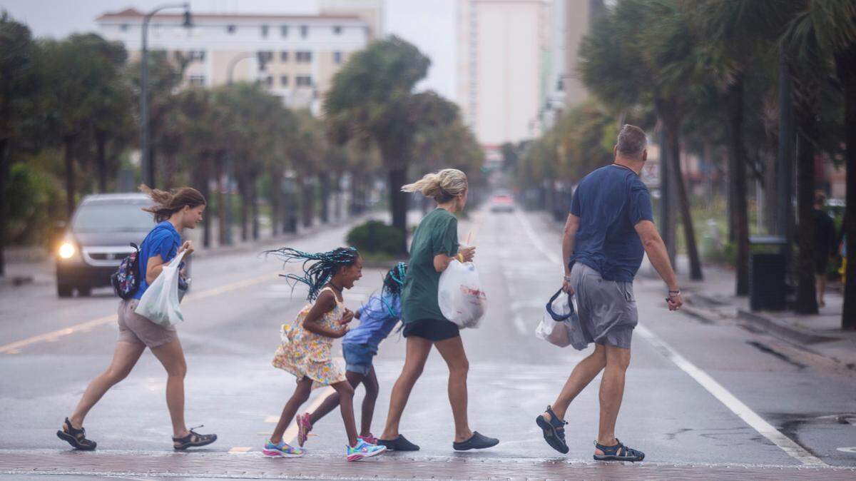 A family walks across the road during wind and rain from Tropical Storm Debby on Wednesday, Aug. 7 in Myrtle Beach. TSN File. 