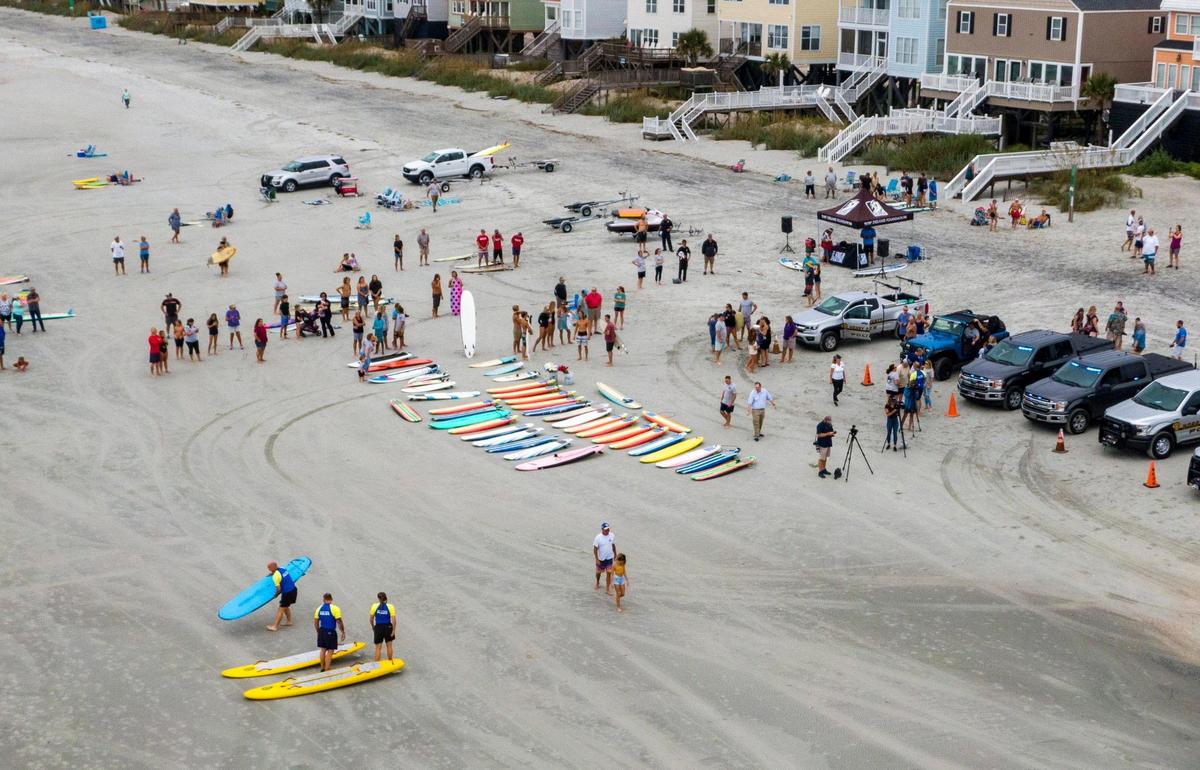A paddle out ceremony was held for the late Cpl. Michael Ambrosino, a beach patrol officer who died of COVID-19 related illness earlier this month. During the ceremony members of HCPD Beach Patrol, local ocean rescue teams, lifeguards, divers, and other friends and family paddled out from the shore arranging themselves in a a human circle, to share a few words about Cpl. Ambrosino and lay flower leis in the surface of the ocean. September 26, 2020.