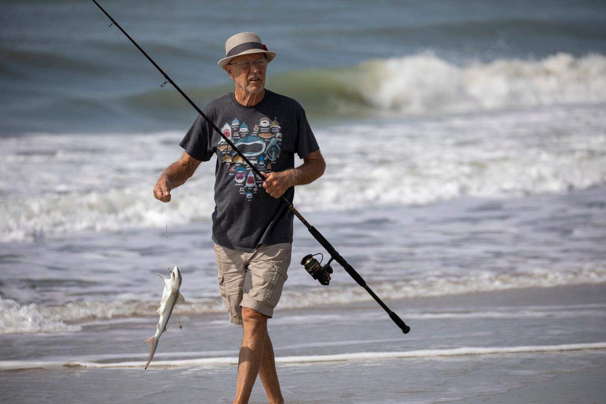 Mike Stranak returns from the surf with a small shark at a surf fishing clinic held by The South Carolina Department of Natural Resources at Huntington Beach State Park on Thursday. July 14, 2022.