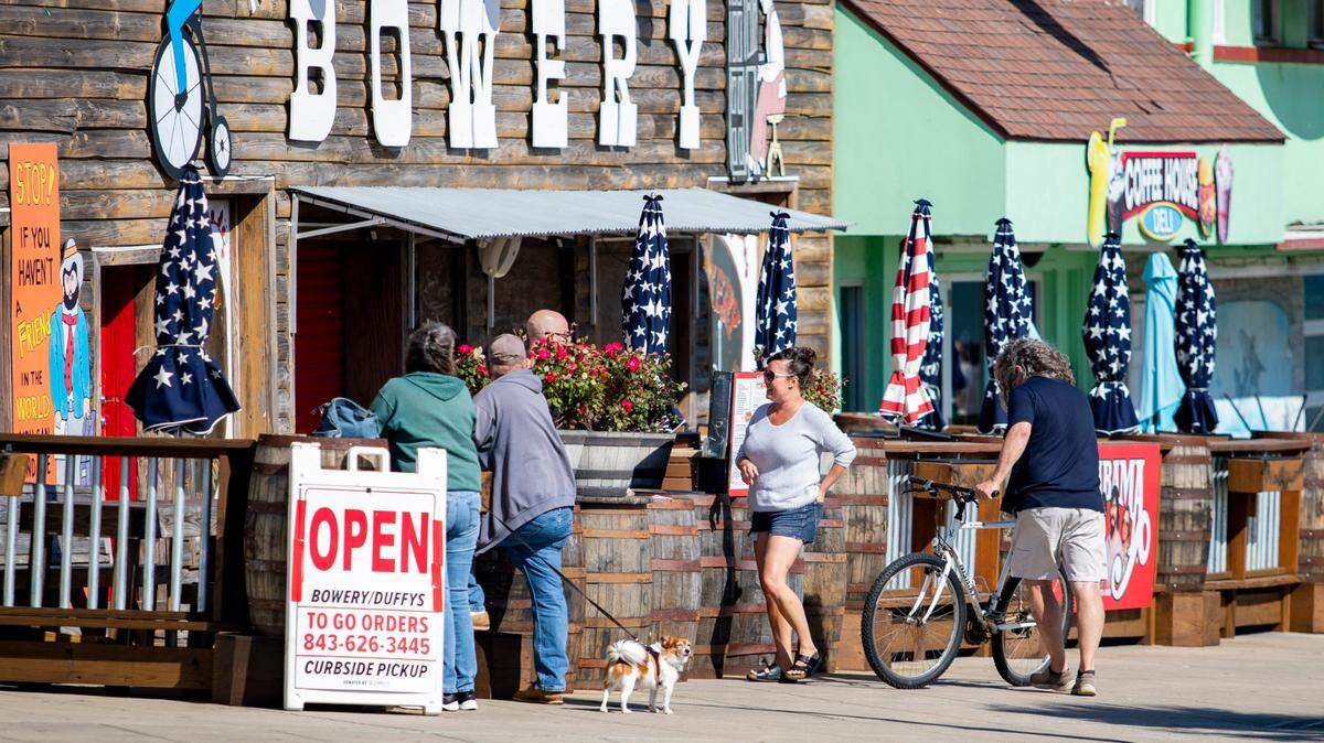 People chat at the Bowery Friday afternoon on the boardwalk in Myrtle Beach as COVID-19 coronavirus cases continue to surface in Horry County.