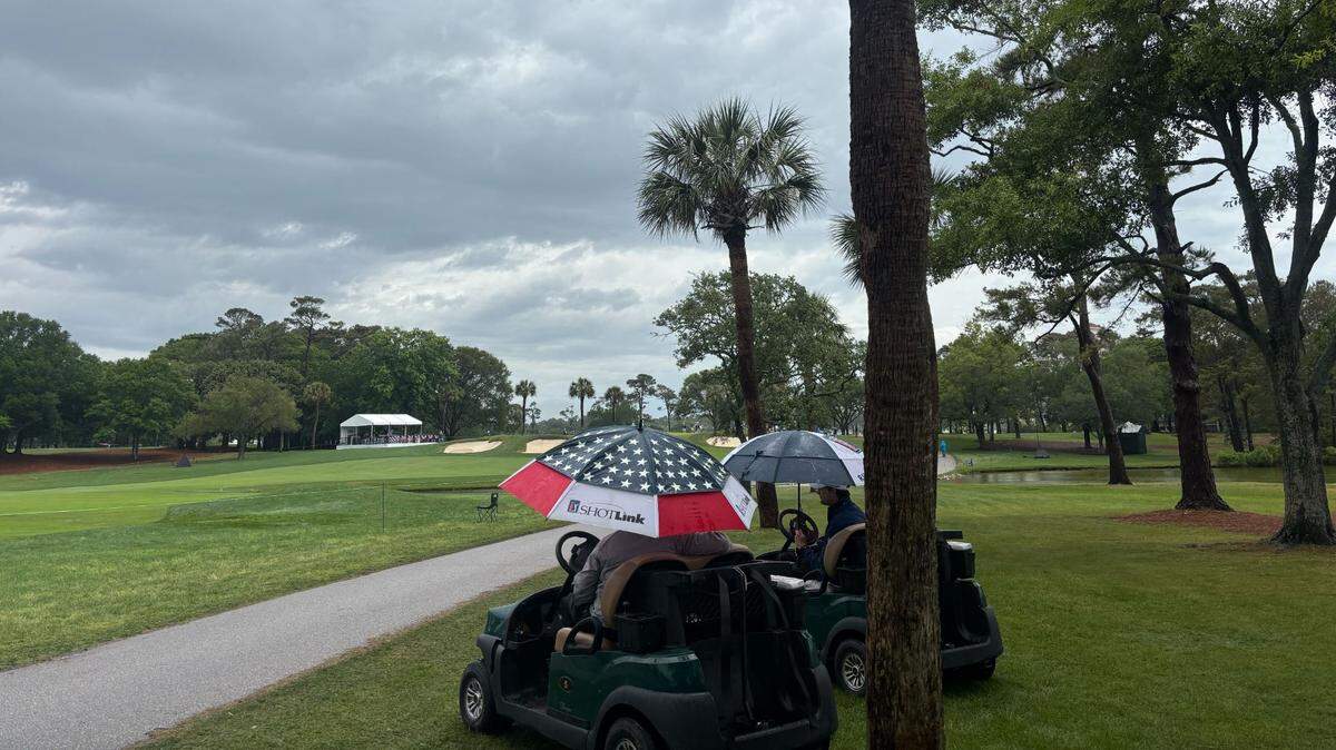 A rainstorm left the Myrtle Beach Classic PGA Tournament empty Sunday morning. Two men sit on golf carts chatting under umbrellas.