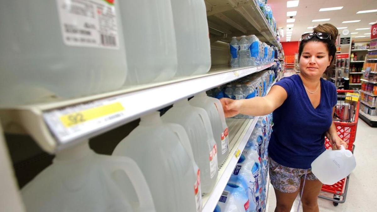 Kelby Schweickerrt, of Destin, Fla., grabs some gallon jugs of drinking water from the shelves at the Target store in Destin, Tuesday, Sept. 5, 2017.