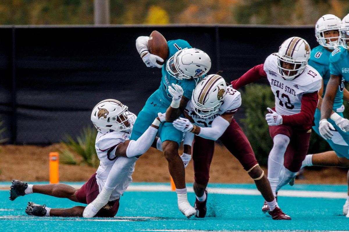 Coastal’s Braydon Bennett tries to hold onto the ball but has it knocked loose by Texas State defenders on Saturday. Coastal ultimately recovered the fumble. Coastal Carolina played Texas State in college football. The Coastal Carolina Chanticleers played the Texas State Bobcats in a Sun Belt Conference NCAA FBS college football game in Conway SC. Nov. 20, 2021.