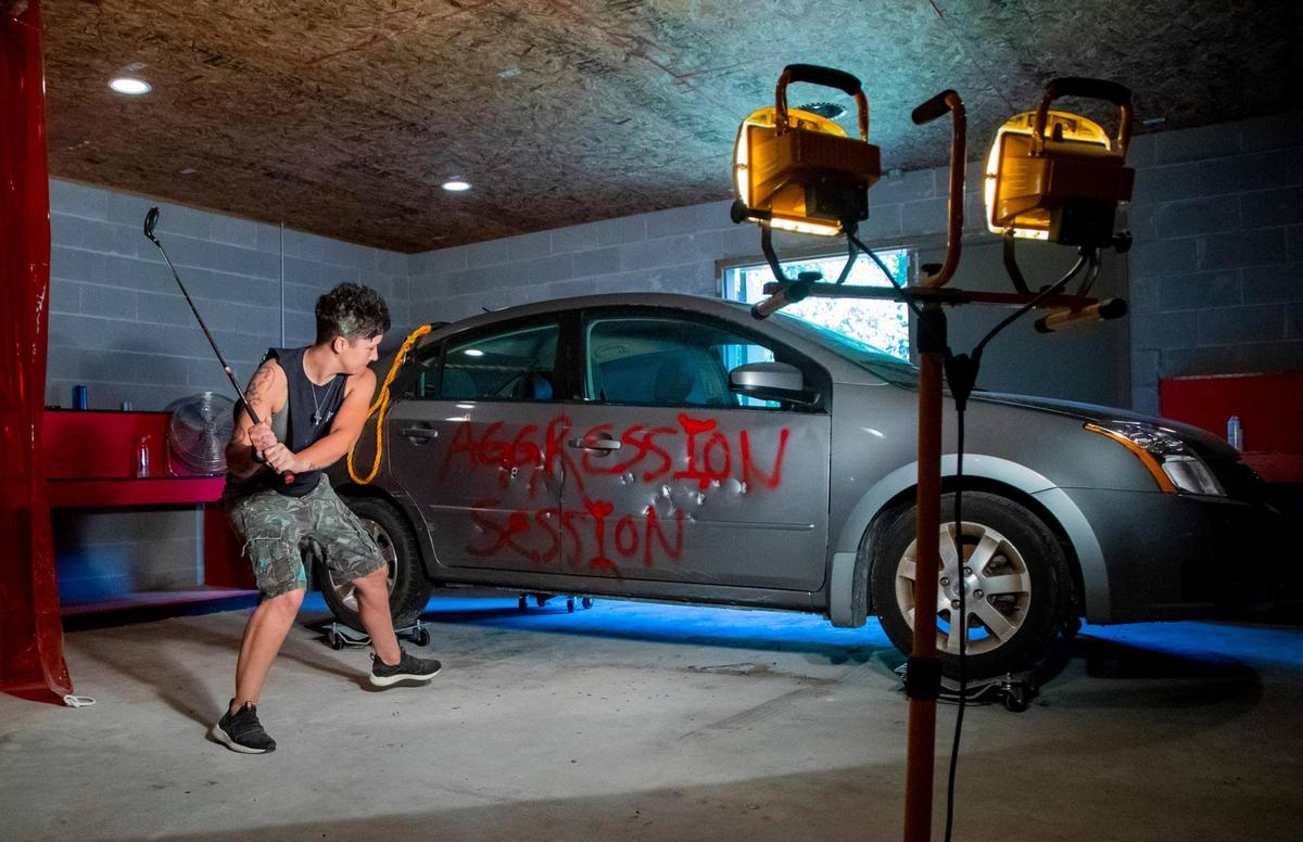 Aggression Session owner Mandy Lowe hits a damaged car with a golf club inside the garage at Aggression Session, a new rage room opening soon in North Myrtle Beach.
