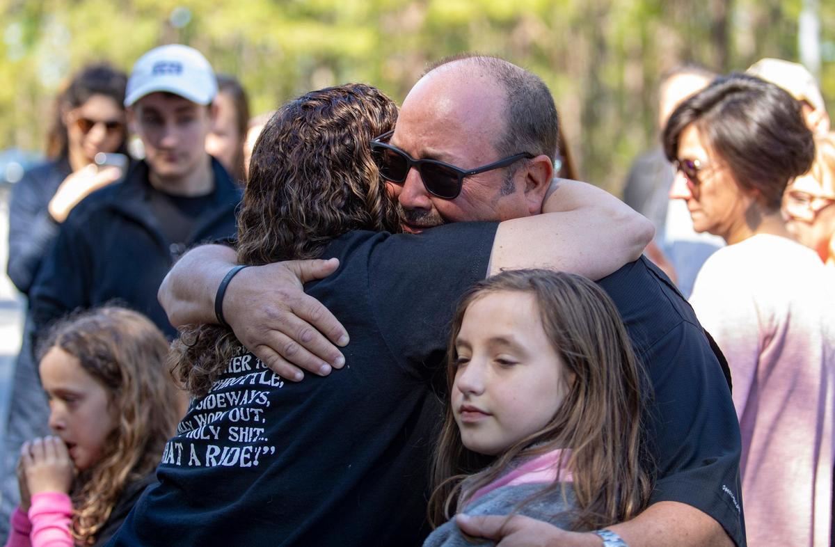Chas Mancuso hugs a family friend at the site of his son Ryan’s death on the one-year anniversary of his son’s passing. Ryan was riding a motorcycle when he was struck by a motorist who was texting.