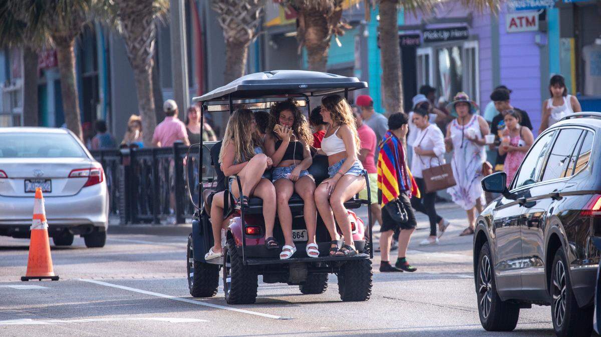 A golf cart travels Ocean Boulevard. Despite a heatwave, crowds arrive packed Myrtle Beach for the July 4th weekend in 2023.