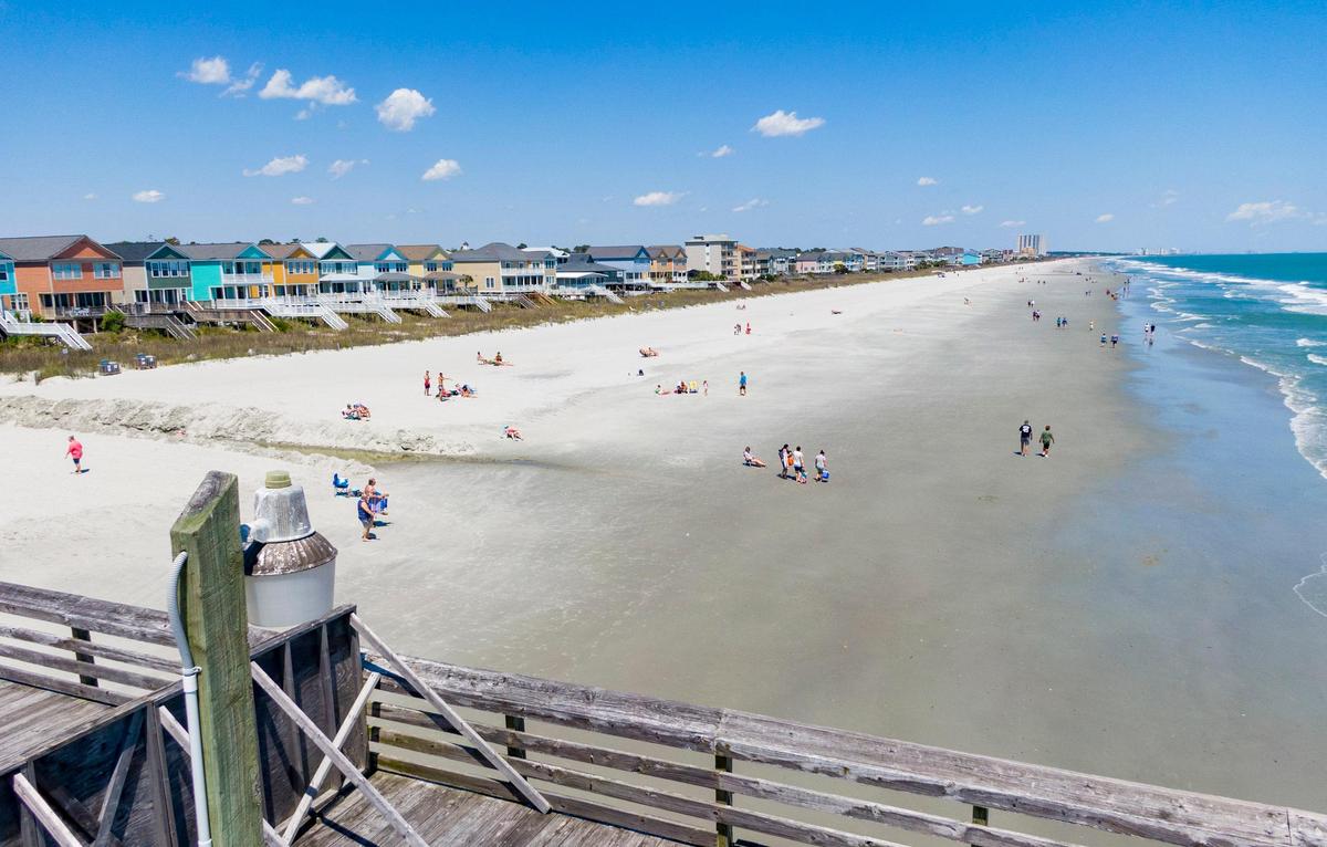 People lay out and walk along the beach near the Surfside Pier Tuesday afternoon in Surfside Beach.