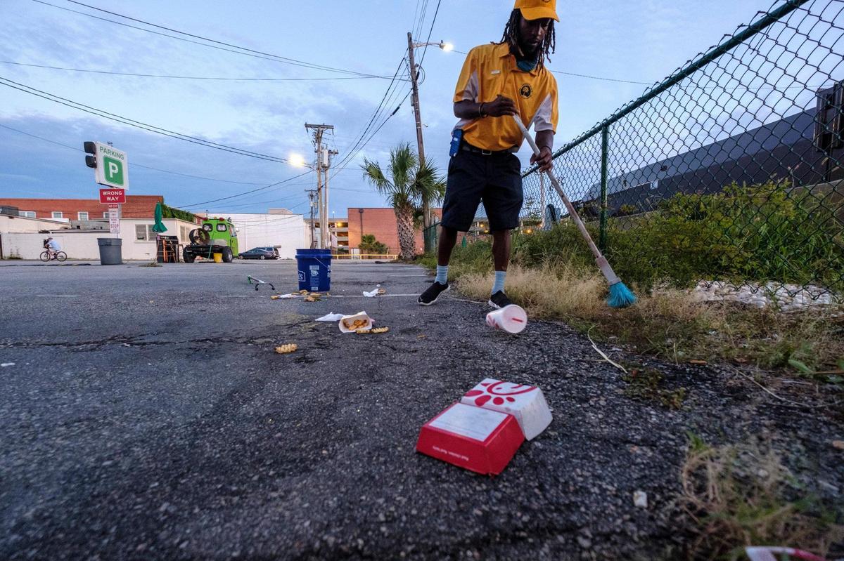 Pierre Owens sweeps up trash left in a parking lot in Myrtle Beach early Saturday morning. Owens is part of a team of a dozen Gold Cap Ambassadors now patrolling the streets of Myrtle Beach cleaning up trash, providing hospitality services, and reporting issues to city officials.The pilot program started in August as a way to improve the safety and cleanliness of the tourism district. August 28, 2020.