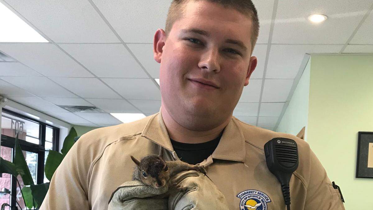 Community Service Officer Jacob Hancher holding a squirrel.