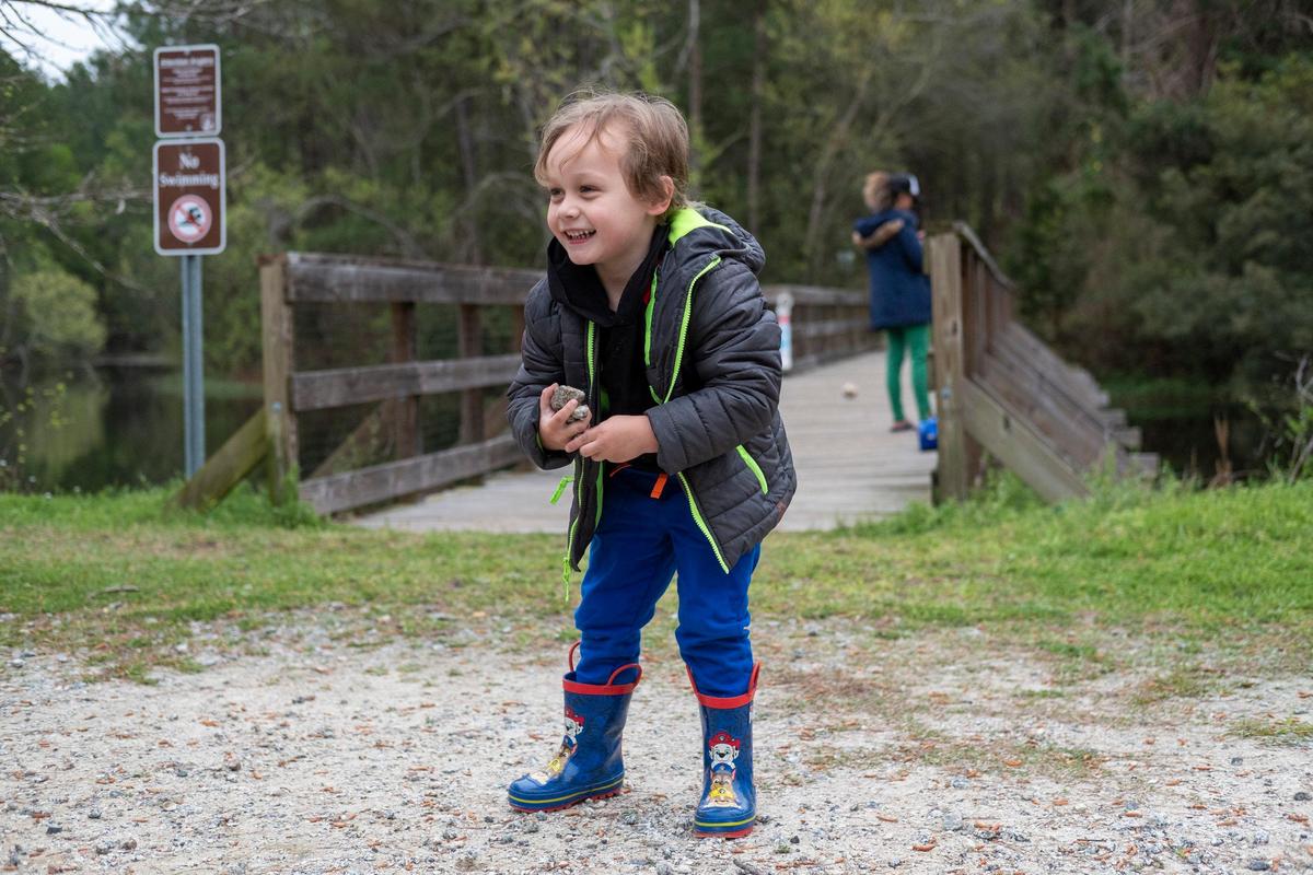 Three-year-old Camden Oliver collects rocks to toss in the water at the Cox Ferry Lake Recreation Area of the Waccamaw National Wildlife Refuge. Oliver along with his mother, Michelle Van Horn, joined family friends to get out of the house on Monday. Locals and visitors are finding outdoor activities to help cope with the stress of the coronavirus. March 23, 2020.