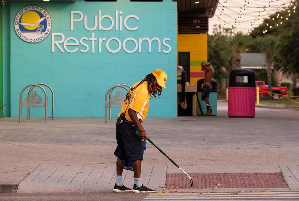 Pierre Owens picks up french fries along Ocean Boulevard in Myrtle Beach early Saturday morning. Owens is part of a team of a dozen Gold Cap Ambassadors now patrolling the streets of Myrtle Beach cleaning up trash, providing hospitality services, and reporting issues to city officials.The pilot program started in August as a way to improve the safety and cleanliness of the tourism district. August 28, 2020.