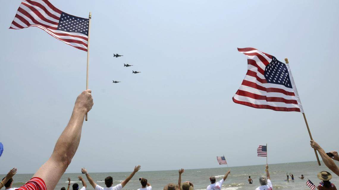 Beachgoers wave American flags as four F-16 fighter jets from Shaw Air Force Base fly the length of the South Carolina coast for the Salute From The Shore in this 2011 file photo.