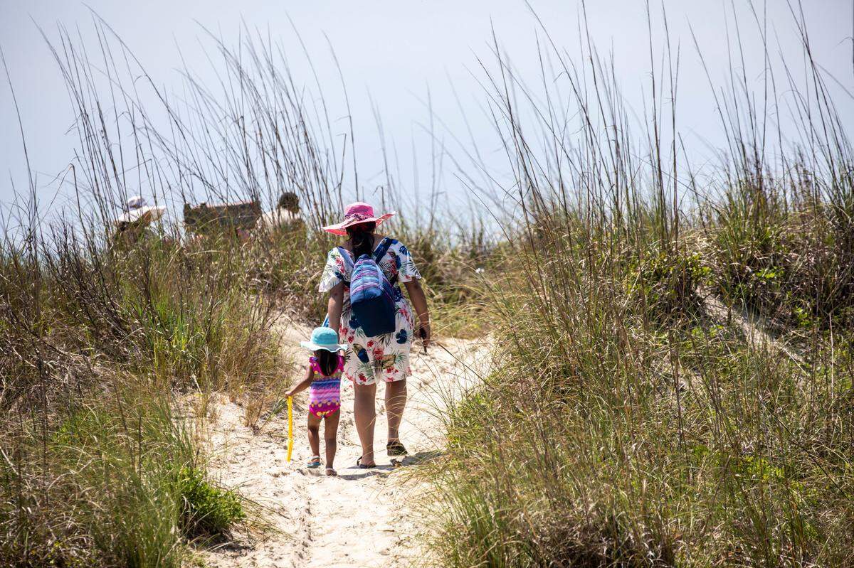 A family makes their way across the dunes to Atlantic Beach. The small historically black beach town, sandwiched between sections of North Myrtle Beach, is undergoing a revitalization according to town manager Benjamin Quattlebaum. New homes are being constructed and oceanfront lots are being marketed to hotels and resorts. June 13, 2022.