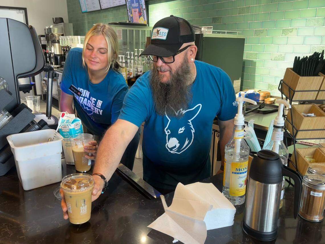 Bad Ass Coffee of Hawaii manager Ron “Crash” Kissell serves an iced coffee during the restaurant's second week of business. The shop uses coffee ice cubes in its drinks to prevent them from becoming watered down. June 23, 2025. 