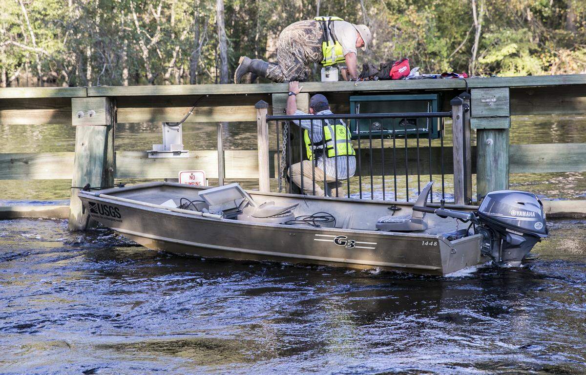 Tom Blowe and Keith Cobb, members of a United States Geological Survey team, move sensitive sensor equipment on the bridge over the Waccamaw in Conway to protect it from rising flood waters. The radar which sends flow and water level readings to the National Weather Service will remain functional by sending data to a receiver at the top of the bridge span. September 19, 2018.