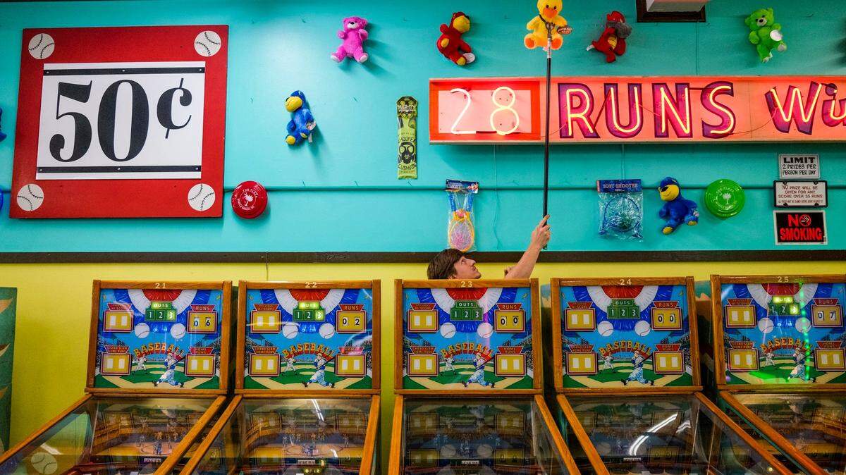 Austin Waldorf, daytime manager of Myrtle Beach’s landmark Fun Plaza arcade, pulls down a prize for the winner of a 1957 William Deluxe Baseball game. Fun plaza maintains 38 of these old machines as well as other classic arcade games. These Myrtle Beach area arcades with their classic games bring back the nostalgia of a bygone era for Grand Strand tourists.July 11, 2022.