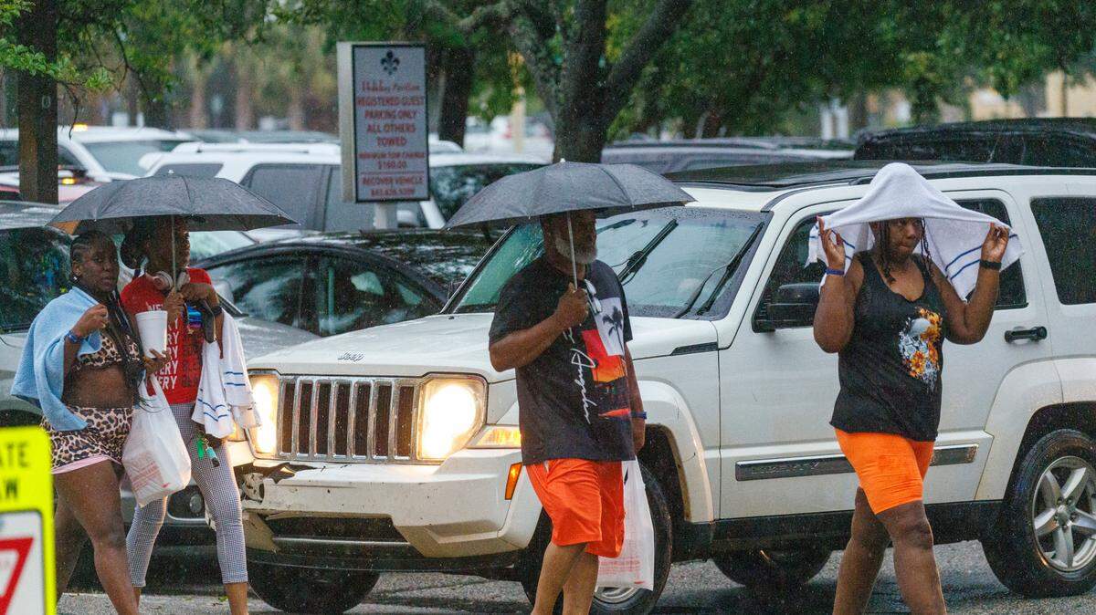 Visitors look for cover from the rain as a storm hits downtown Myrtle Beach. Friday, May 30, 2025.
