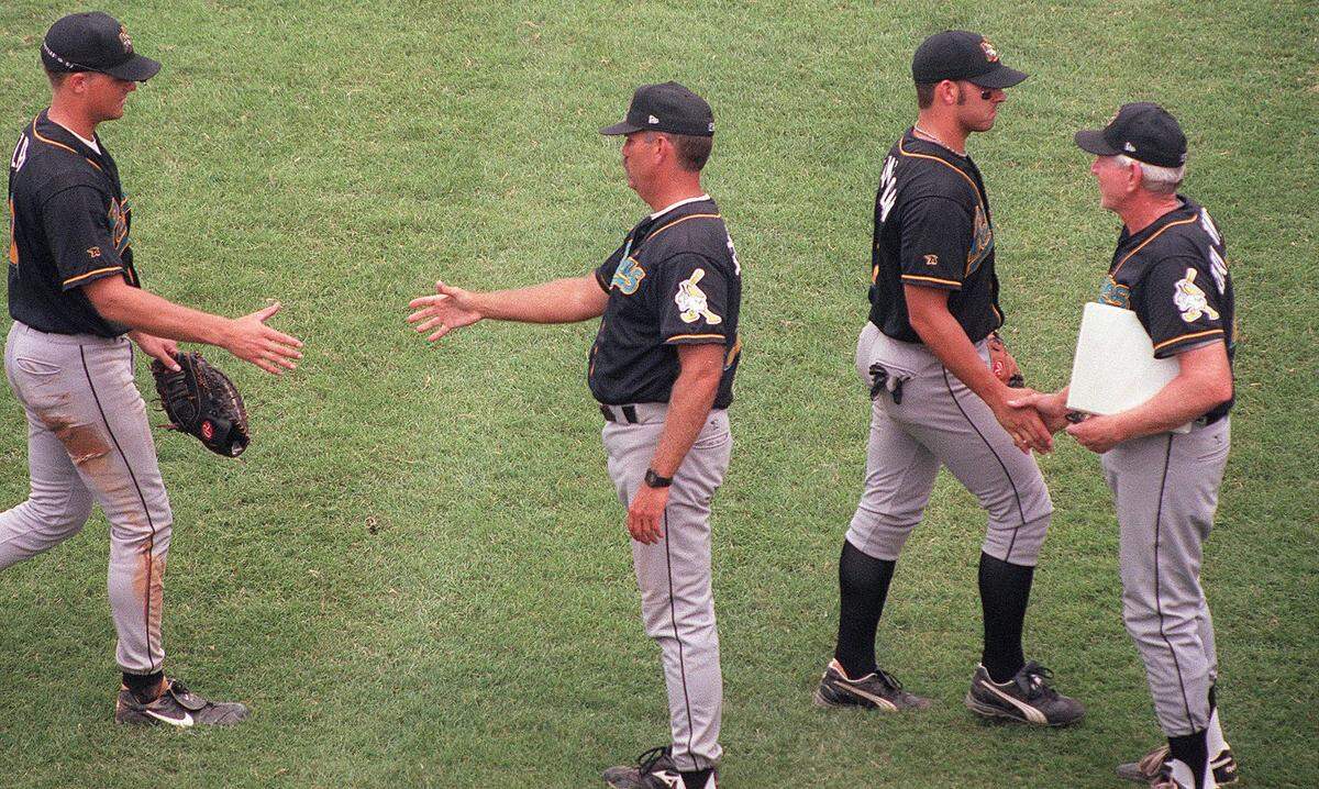 Pelicans manager Brian Snitker (second from left) and pitching coach Bruce Dal Canton (right) congratulate the team for a win.