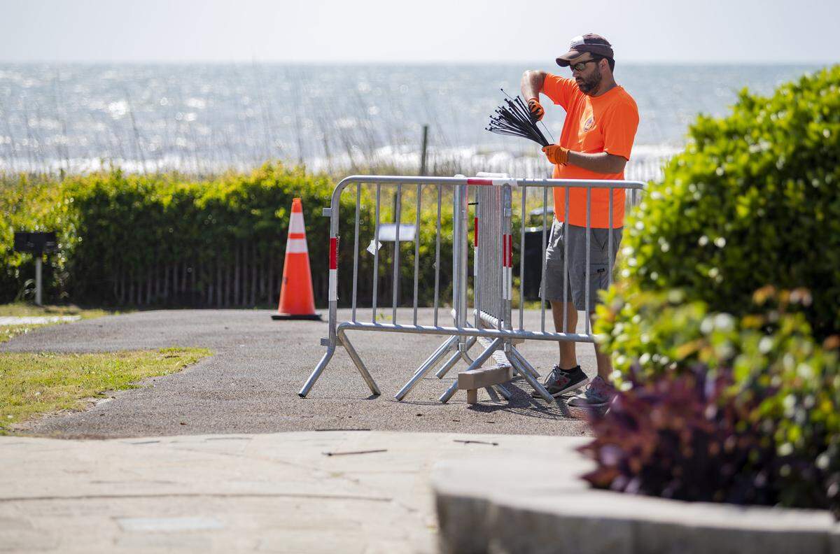 A Myrtle Beach Recreation Services employee zipties barricades around a balance beam at an oceanside playground Wednesday morning along Ocean Boulevard in Myrtle Beach.