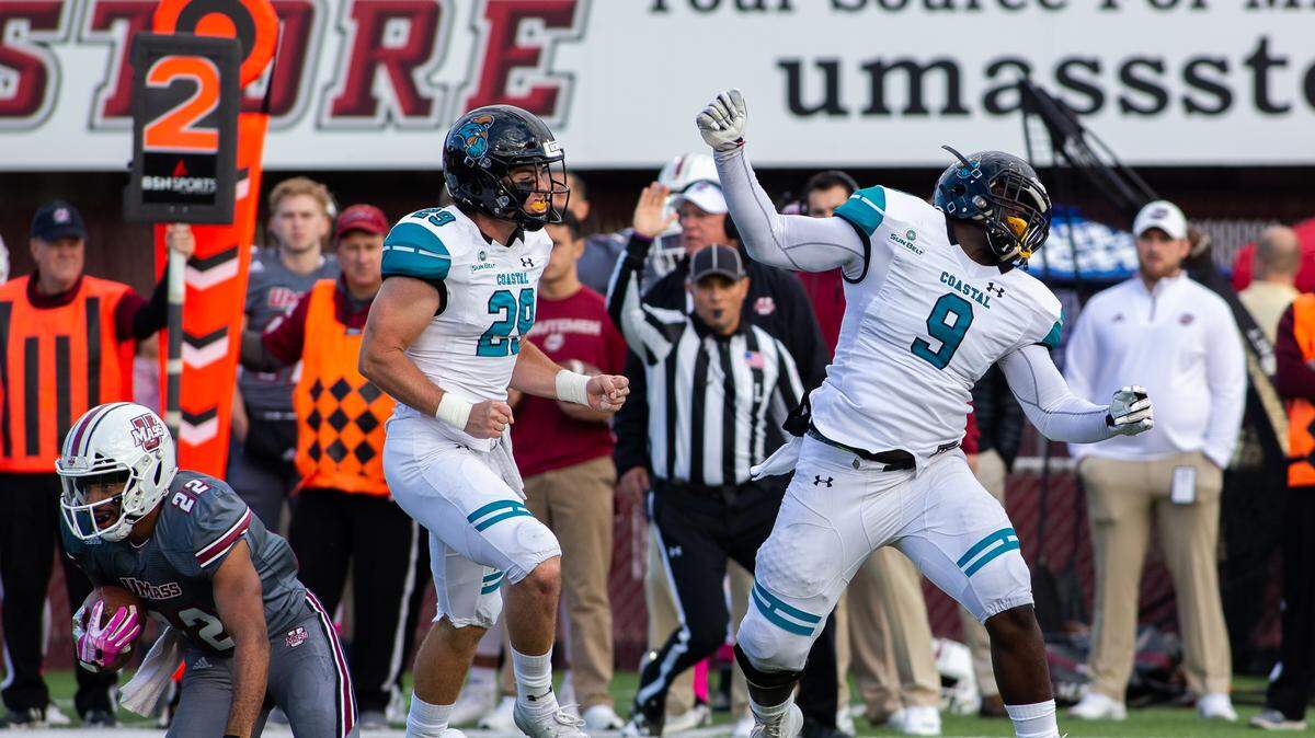 Coastal Carolina linebacker Silas Kelly (29) and defensive end Tarron Jackson (9) celebrate a tackle of Massachusetts running back Bilal Ally on Saturday at Warren McGuirk Alumni Stadium in Amherst, Mass.