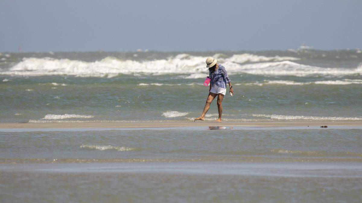 Beachcombers walk an area of North Myrtle Beach called “The Point” that looking through tidal pools for in search of shells. Wednesday, April 24, 2024.