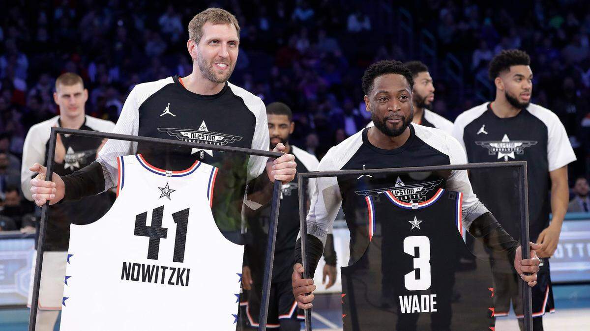 CORRECTS TO DWYANE, NOT SWAYNE - Team Giannis’ Dirk Nowitzki, of the Dallas Mavericks, and Team LeBron’s Dwyane Wade, of the Miami Heat, are given jerseys during the second half of an NBA All-Star basketball game, Sunday, Feb. 17, 2019, in Charlotte, N.C. The Team LeBron won 178-164. (AP Photo/Chuck Burton)