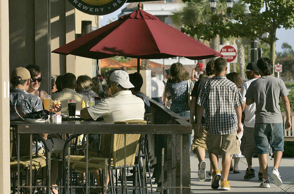 People stroll past the sidewalk seating at Gordon Biersch Brewery Restaurant in the Market Common. - Photo by Tom Murray