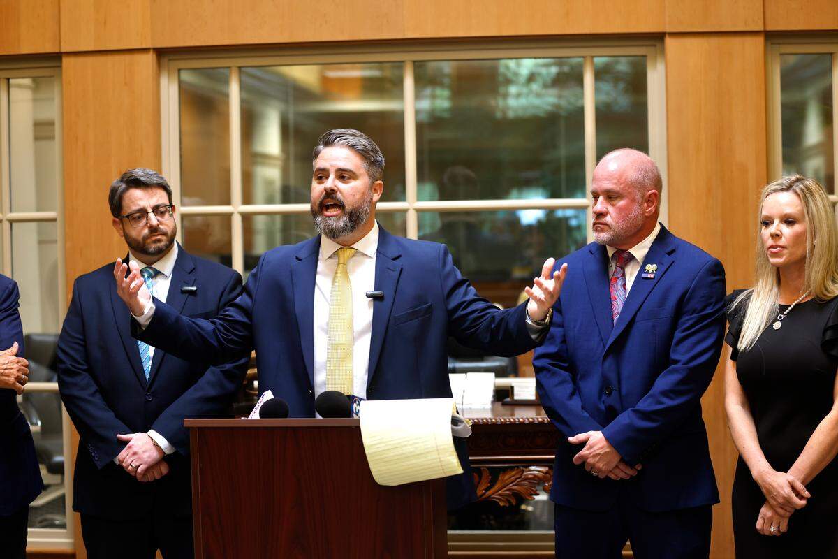From left to right: Attorneys Tristan Shaffer and Jonny McCoy stand with former Captain Danny Furr at a news conference on April 30, 2026.