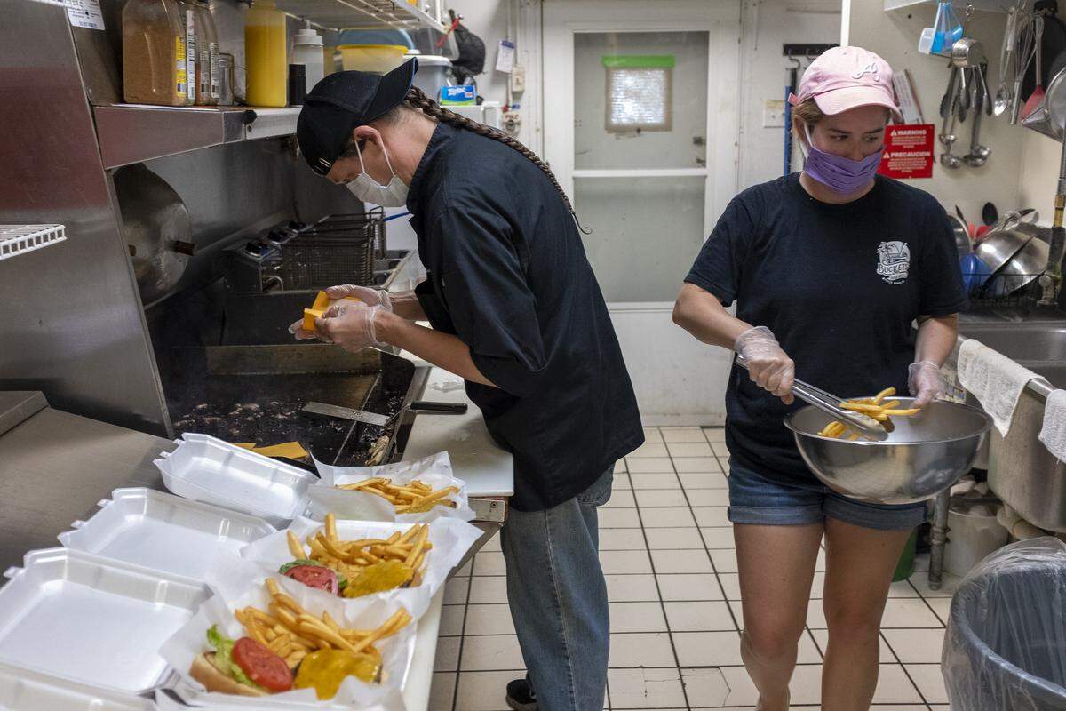 Lauren Preuter and Katie Thompson work in the kitchen at Buckets Bar and Grill to make cheeseburgers and fries for local firefighters. April 30, 2020