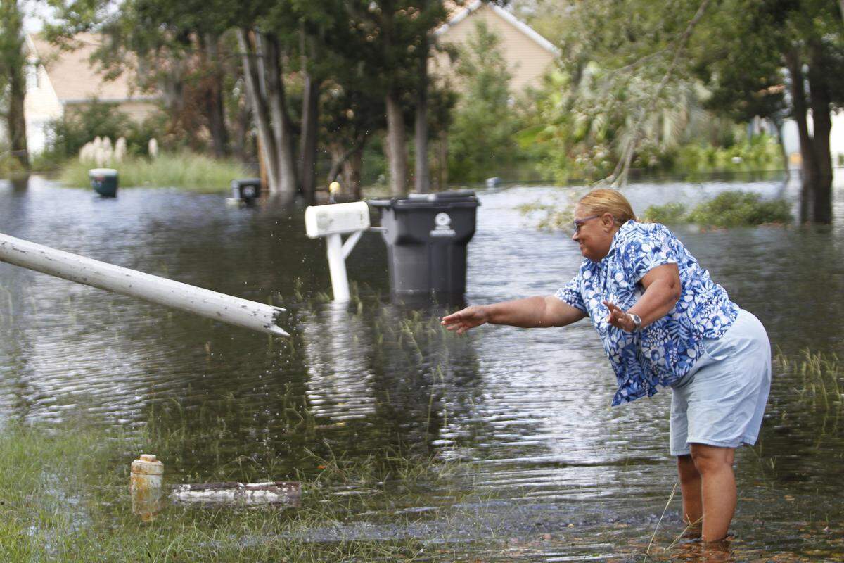 Linda Pelletier moves pieces of wood in her Socastee yard as floodwater rises in the Intracoastal Waterway just across from her home. Sept. 24, 2018