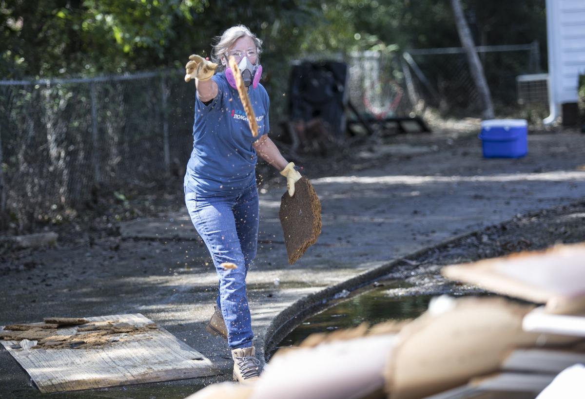 Sue Howard throws debris on a pile while helping to muck out Joey Tyler’s home on Sherwood Drive in Conway. Howard came to volunteer in South Carolina under Impact Ministries of Myrtle Beach after working the past week in North Carolina to muck out eight homes in that flooded region.  The many volunteers that are helping with flood victims are organized under the Waccamaw VOAD (Voluntary Organizations Active in Disasters.) October 1 2018.