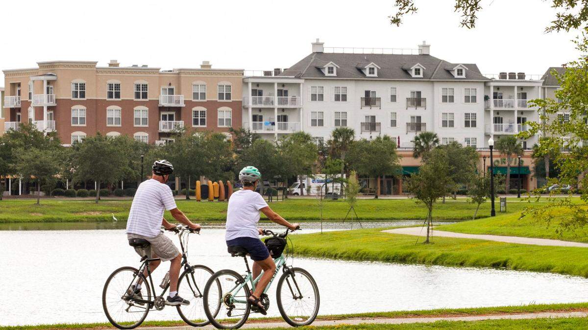 A couple rides bicycles around the lake in Market Common in Myrtle Beach. Three SC cities were named best places to live in the South in June 2023. File photo.