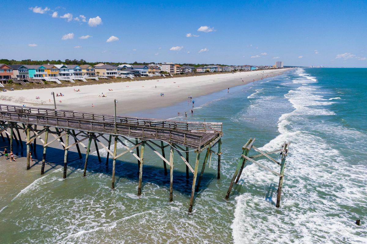 People lay out and walk along the beach near the Surfside Pier Tuesday afternoon in Surfside Beach.