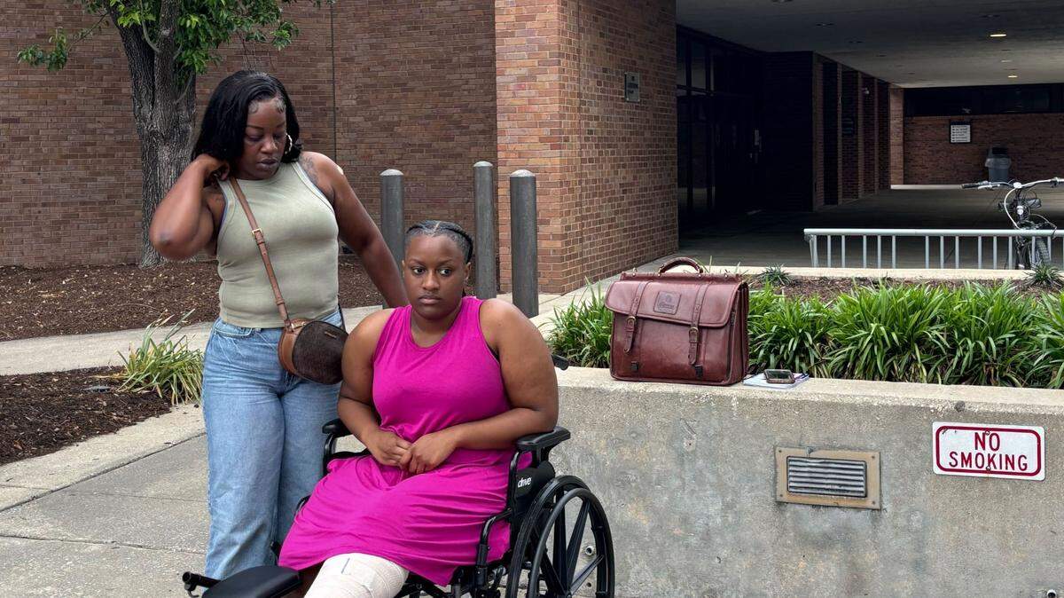 Serenity Chavis sits in a wheelchair next to her mother, Kendra Malloy, and lawyer John C. Barnett outside the Myrtle Beach police station on Oak Street. May 7, 2025