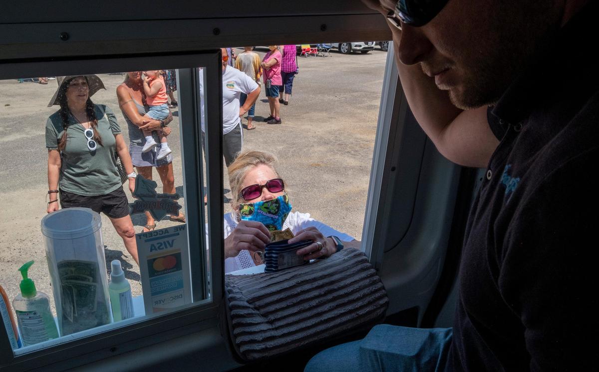 Booze Pops owner Adam Eversen serves June Johnson at from the window of his truck in the Island Green community. With most of the spring events canceled in the Myrtle Beach area, the Booze Pops truck has been making the rounds of local communities, “bringing the bar” to people stuck at home. May 5, 2020