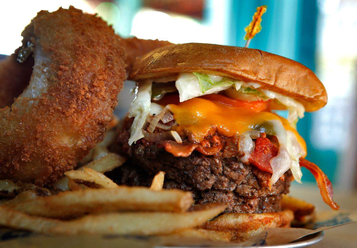 Restaurants are coming up with unique takes on an old American standby -- the hamburger. When ordering the Kitchen Sink Burger Platter at River City Cafe 404 21st Avenue North in Myrtle Beach, you get two patties stacked with Texas chili, applewood smoked bacon, grilled onions, jalappenos, mushrooms, swiss and cheddar cheese, pickles, mayo, mustard, served with a pile of fries, two giant onion rings and slaw. Photo by Steve Jessmore sjessmore@thesunnews.com