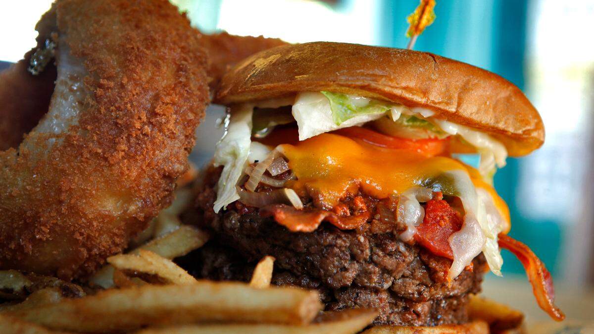 When ordering the Kitchen Sink Burger Platter at River City Cafe 404 21st Avenue North in Myrtle Beach, you get two patties stacked with Texas chili, applewood smoked bacon, grilled onions, jalapenos, mushrooms, Swiss and cheddar cheese, pickles, mayo, mustard, served with a pile of fries, two giant onion rings and slaw. Photo by Steve Jessmore sjessmore@thesunnews.com
