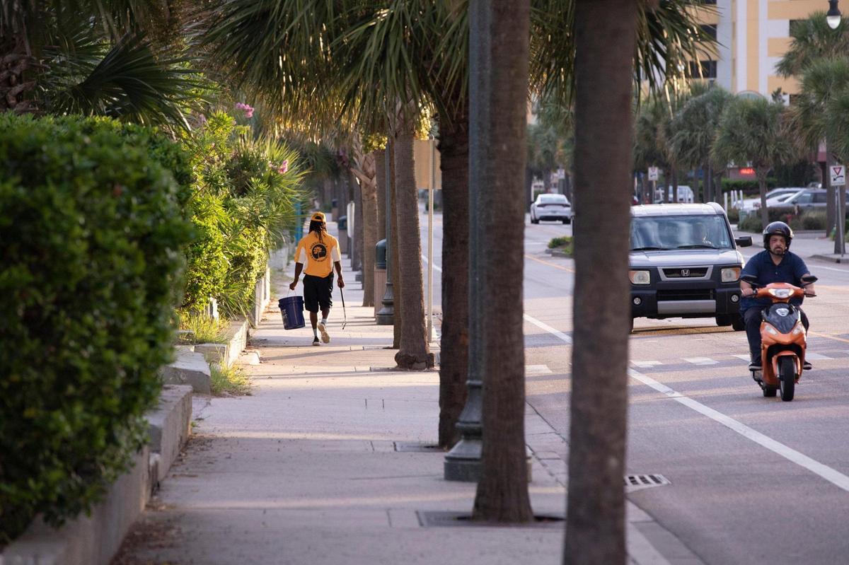 Pierre Owens walks the sidewalks along Ocean Boulevard with his trash picker and bucket early Saturday morning. Owens is part of a team of a dozen Gold Cap Ambassadors now patrolling the streets of Myrtle Beach cleaning up trash, providing hospitality services, and reporting issues to city officials.The pilot program started in August as a way to improve the safety and cleanliness of the tourism district. August 28, 2020.