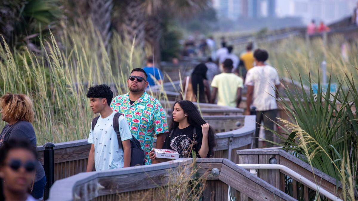 Tourists walk the Myrtle Beach Boardwalk on Saturday. Despite a heatwave, crowds arrive in Myrtle Beach for the July 4th weekend on Saturday. Tourists packed beaches, cruised the boulevard and enjoyed fireworks at the Myrtle Beach Pelicans baseball game. July 1, 2023.