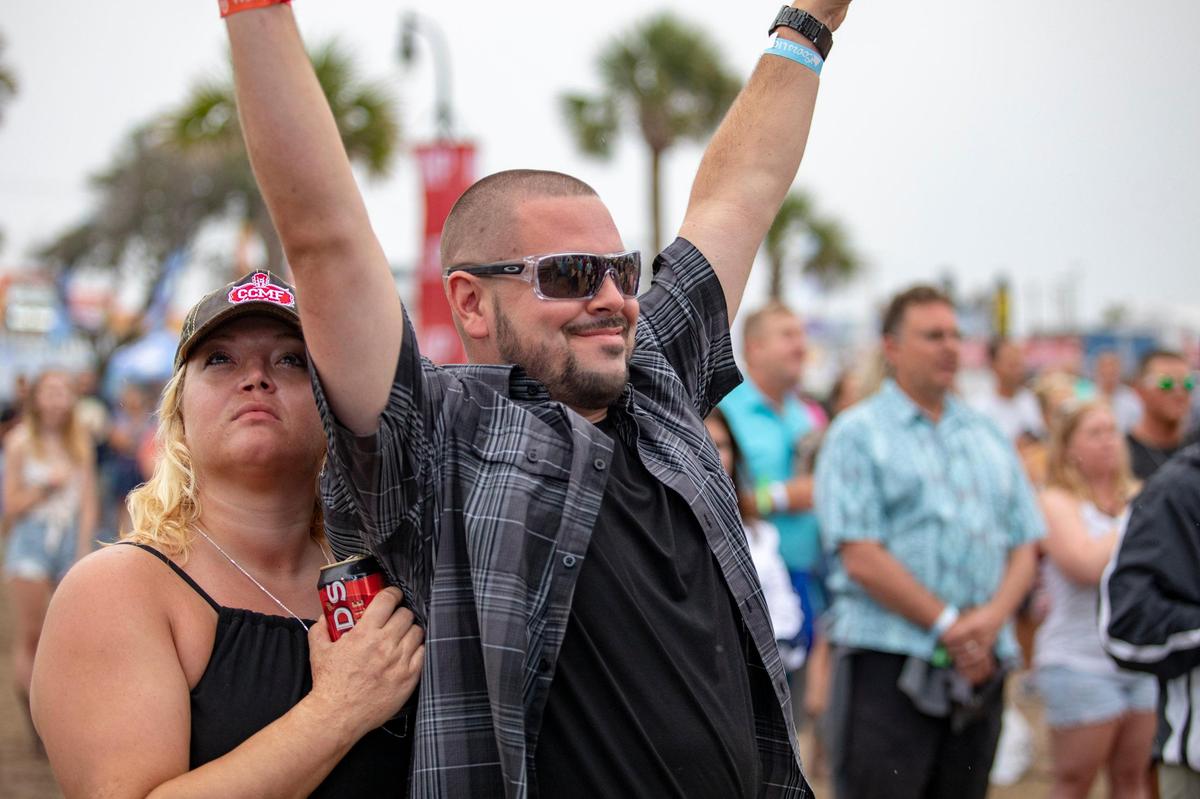 Jason Brooks of Lynchburg, Va. raises his hands as Gyth Rigdon performs the National Anthem Thursday afternoon during Carolina Country Music Fest.