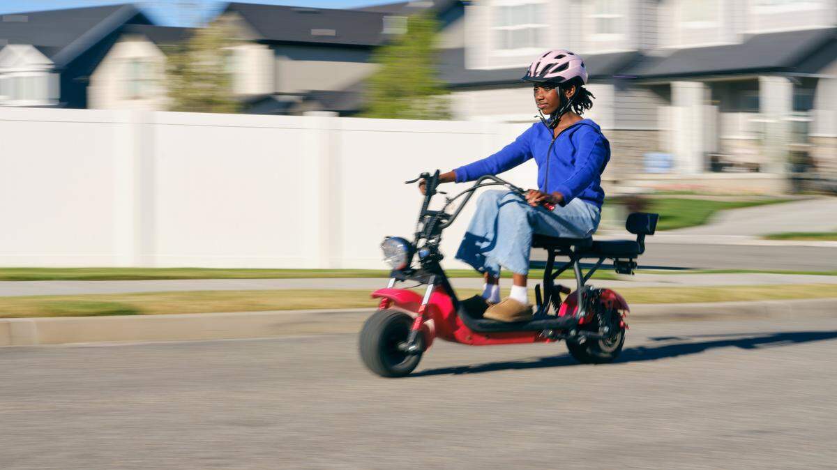 A pre-teen girl riding an electric scooter in a residential neighborhood.