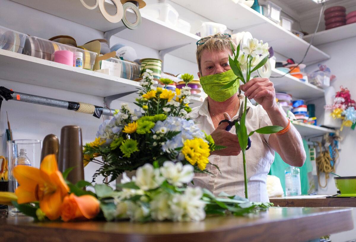 Wearing a mask, Jodie Wilson prepares fresh flower arrangements after Daisy Fair flowers in Conway re-opened this week. With Mother’s Day in just two weeks, florists are in a difficult position determining whether to open or remain closed during the coronavirus. April 23, 2020