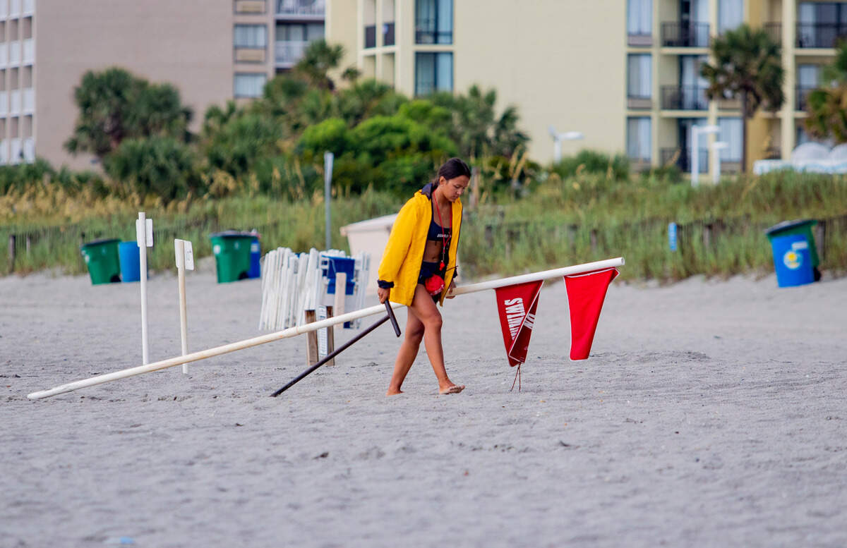 A lifeguard removes a “No Swimming” flag Saturday afternoon in Myrtle Beach as Hurricane Isaias approaches the eastern seaboard.