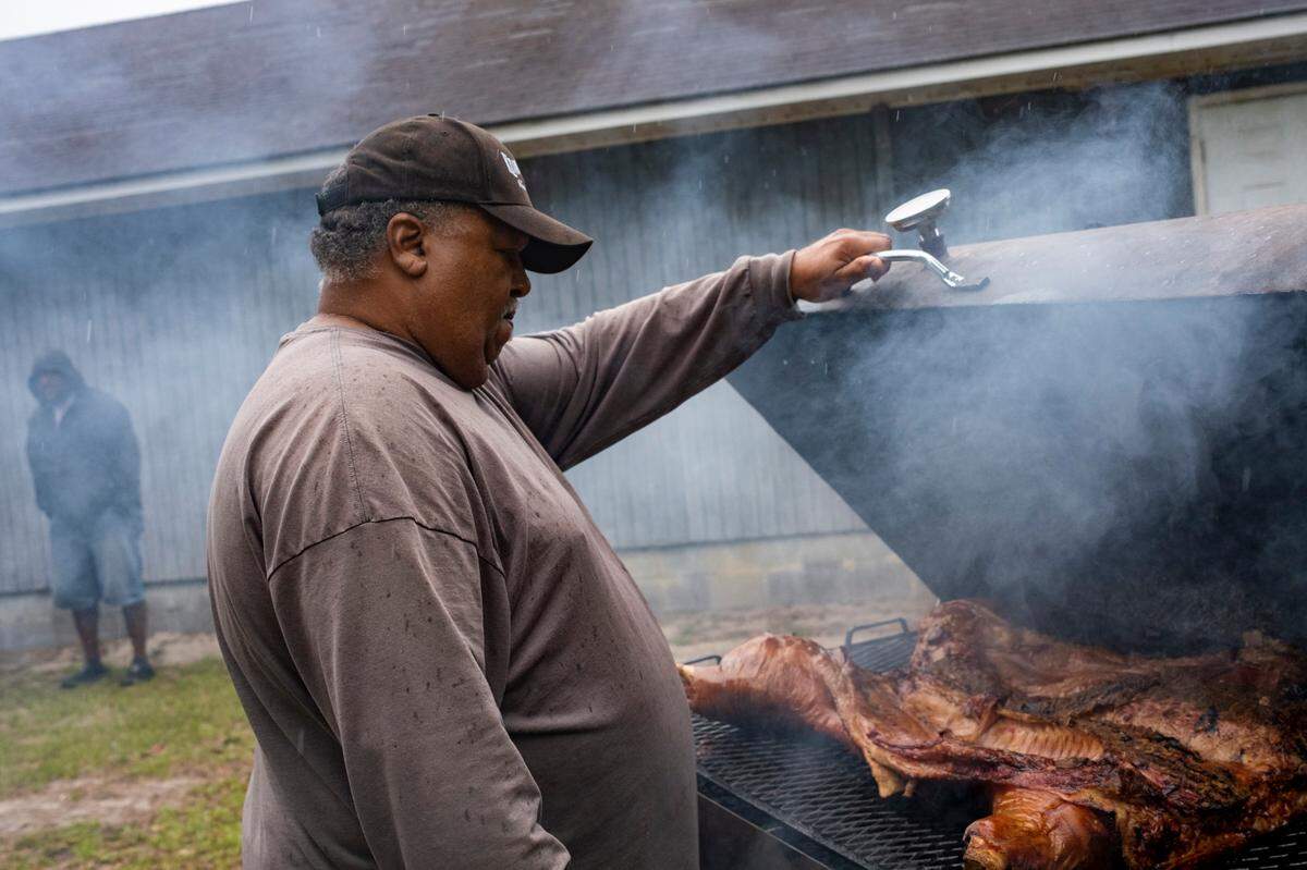 Dwayne Todd cooks a pig outside the Carolina Knight Rider’s clubhouse in Longs, S.C. while waiting on members to arrive at the club on Friday evening. May 26, 2023.