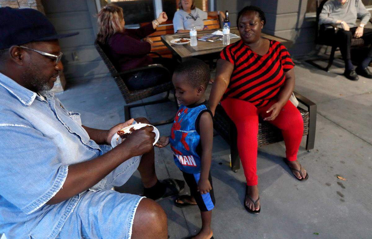 Winston Jordan, left, and his daughter Khadijah Jordan and grandson Josiah Brown, 4, enjoy the food cooked by South Carolina Department of Natural Resources in Myrtle Beach, S.C., Thursday, Sept. 13, 2018.