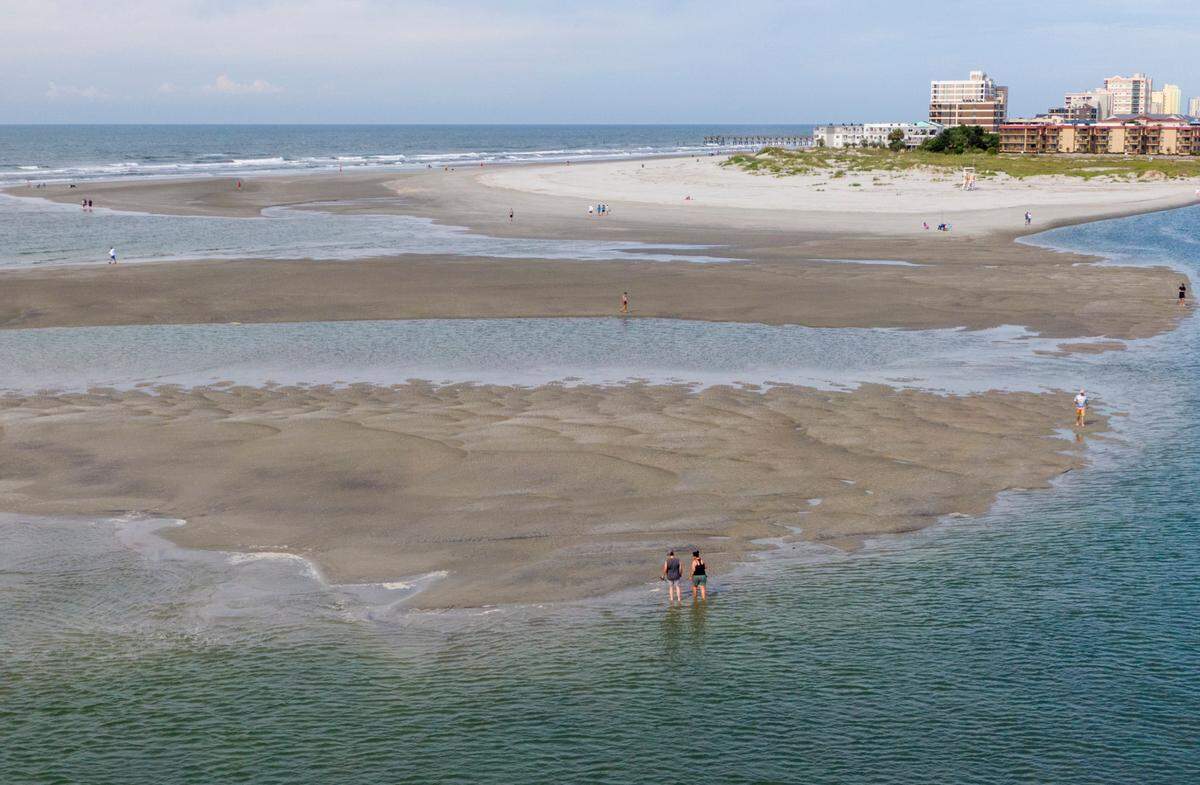 Beach goers enjoy the sand bars and tidal pools at the tip of Cherry Grove in North Myrtle Beach, S.C. The area, also known as Cherry Grove Point, has sand bars and tidal pools exposed during low tide.