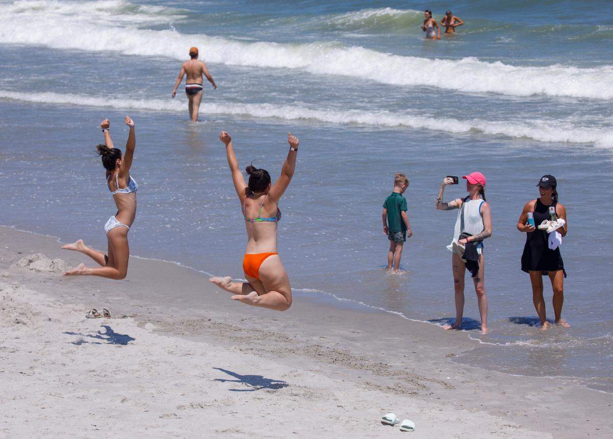 Visitors jump for a picture on the beach. The week of July 4th is one of the times for tourism in the Myrtle Beach area. July 2, 2024.