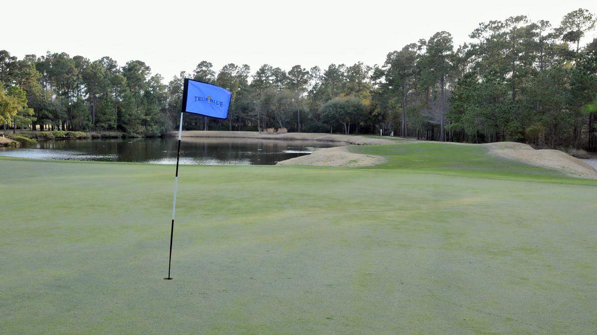 The par-3 16th at True Blue Golf Club features bunkers and water.