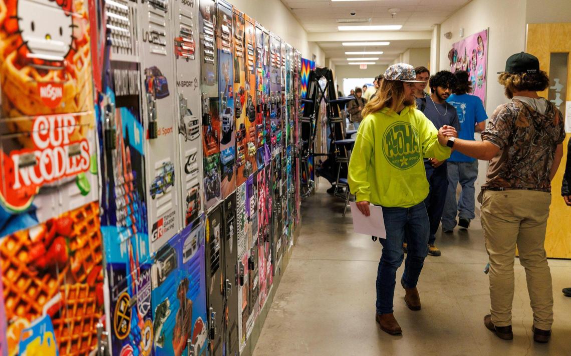 Students great each other in front of lockers covered in decals created in the Digital Arts and Graphics shop at The Palmetto Academy for Learning Motorsports (PALM). The charter high school in Conway, SC uses motorsports as a foundation for educating students. In additional to their regular curriculum, high school students work in Welding, Digital Arts & Graphics, Auto Collision Technology and Motor Sports Technology to learn skills that can be applied to various trades. Oct. 30, 2024.